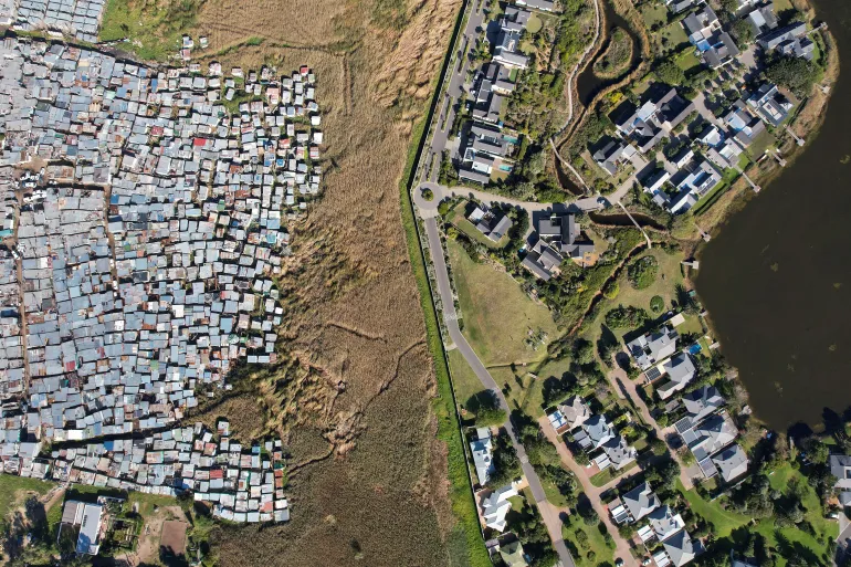 Informal shacks in a majority-Black township are seen next to an upmarket private estate in Cape Town. Land and spatial inequality still plague South Africa 30 years after the end of apartheid [Nic Bothma/Reuters]